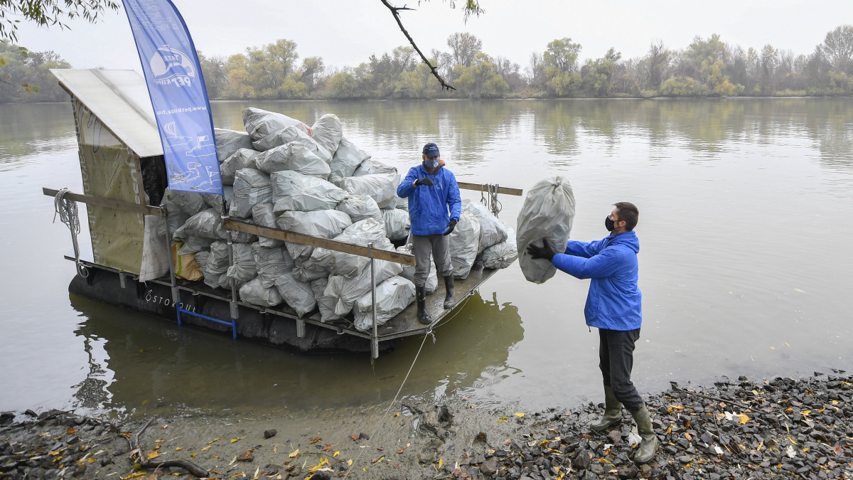 Önkéntesek PET-palackokkal töltött zsákokat pakolnak le egy kishajóról a Tisza partján, Tiszaszőlős közelében 2020. november 11-én. A Tisztítsuk meg az országot! programban a Közép-Tisza-vidéki Vízügyi Igazgatóság és a Tisza-tavi Sporthorgász Közhasznú Nonprofit Kft. munkatársai, valamint a Tiszai PET Kupa önkéntesei takarítják a Tisza-tavat és környékét.