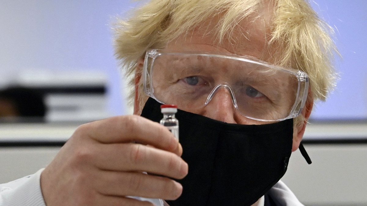 Boris Johnson brit miniszterelnök az AstraZeneca svéd-brit gyógyszergyár és az Oxfordi Egyetem által közösen fejlesztett potenciális koronavírus elleni vakcinát (AZD1222) tartalmazó fiolát tart a kezében a Wockhardt indiai székhelyű gyógyszeripari vállalat telephelyén, a walesi Wrexhamben 2020. november 30-án.