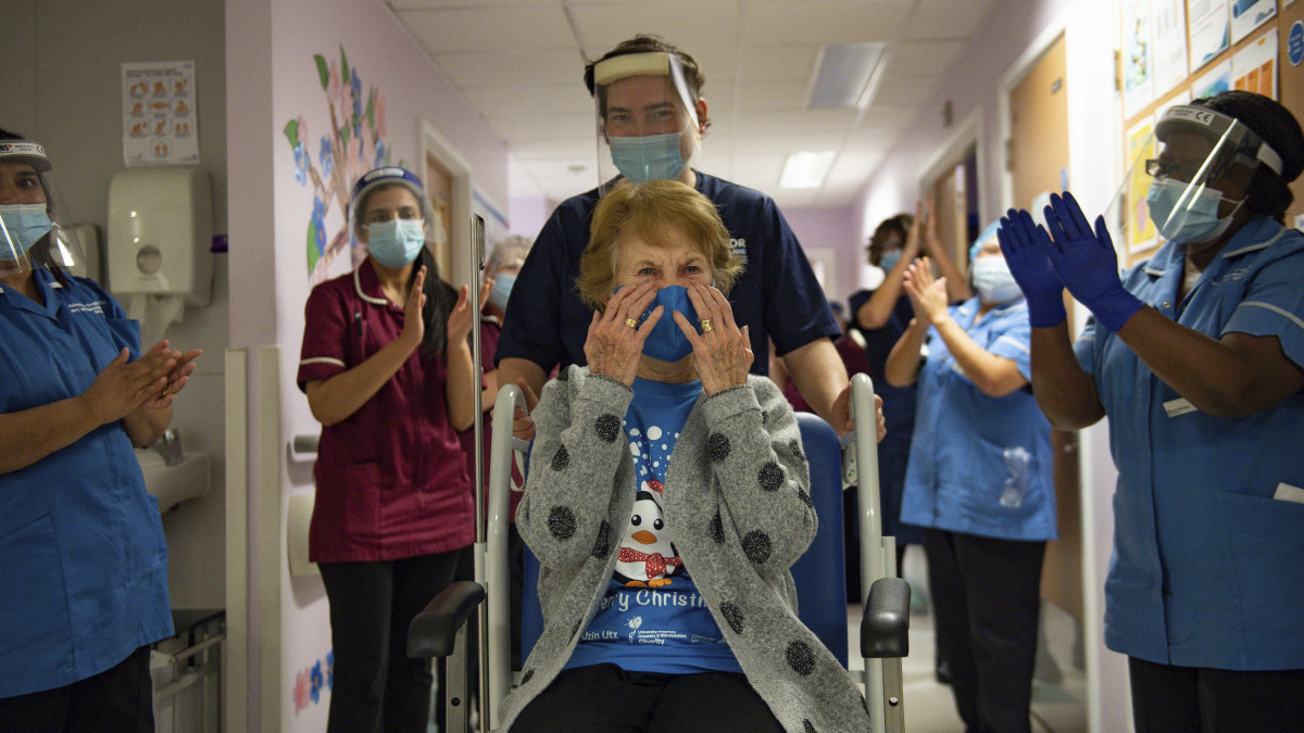 A 90 éves Margaret Keenant (k) megtapsolják a folyosón, miután megkapta a Pfizer-BioNTech oltóanyagkifejlesztő vállalatok koronavírus elleni vakcináját az angliai Coventry egyik kórházában 2020. december 8-án. Az Egyesült Királyságban ezen a napon megkezdték az új típusú koronavírus elleni tömeges oltási kampányt. Keenan volt az első páciens, akinek beadták az oltást.