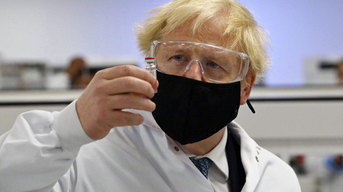 Boris Johnson brit miniszterelnök az AstraZeneca svéd-brit gyógyszergyár és az Oxfordi Egyetem által közösen fejlesztett potenciális koronavírus elleni vakcinát (AZD1222) tartalmazó fiolát tart a kezében a Wockhardt indiai székhelyű gyógyszeripari vállalat telephelyén, a walesi Wrexhamben 2020. november 30-án.