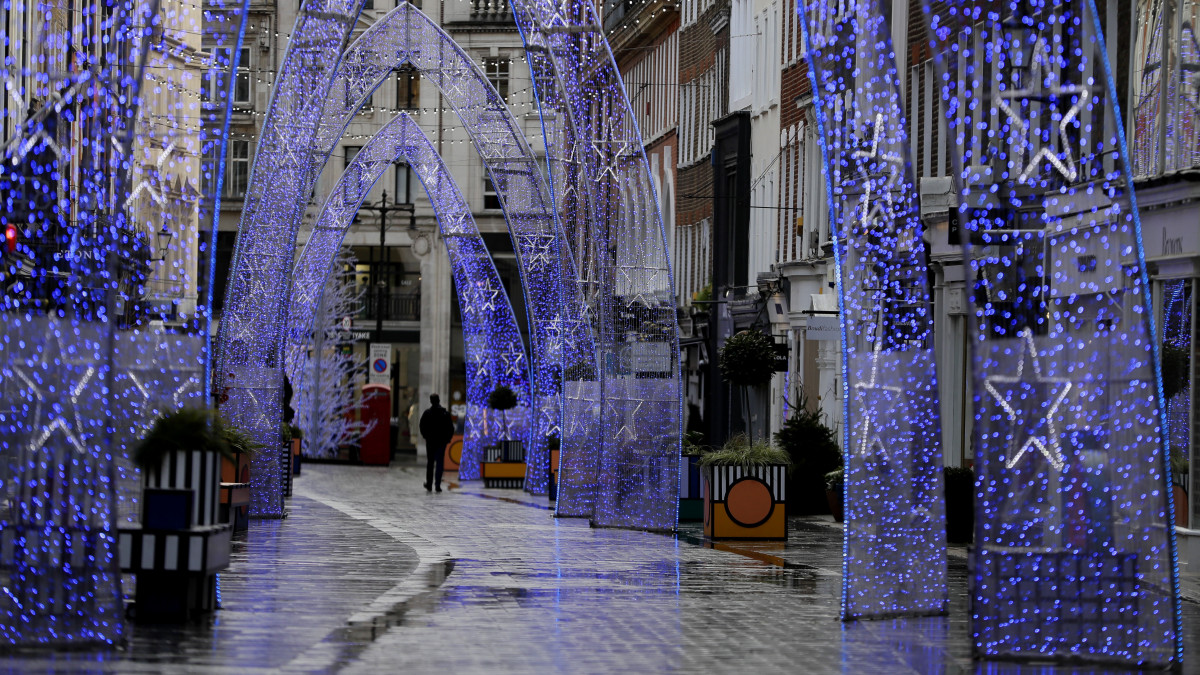 A londoni South Molton Street karácsonyi díszei alatt egy járókelő 2020. december 23-án, amely általában az év egyik legforgalmasabb bevásárlónapja. A koronavírus új változatának terjedésétől leginkább érintett térségekben, elsősorban Londonban és Délkelet-, illetve Kelet-Angliában a háromfokozatú járványkészültségi rendszert december 20-tól kiegészíti egy újabb, negyedik fokozat.