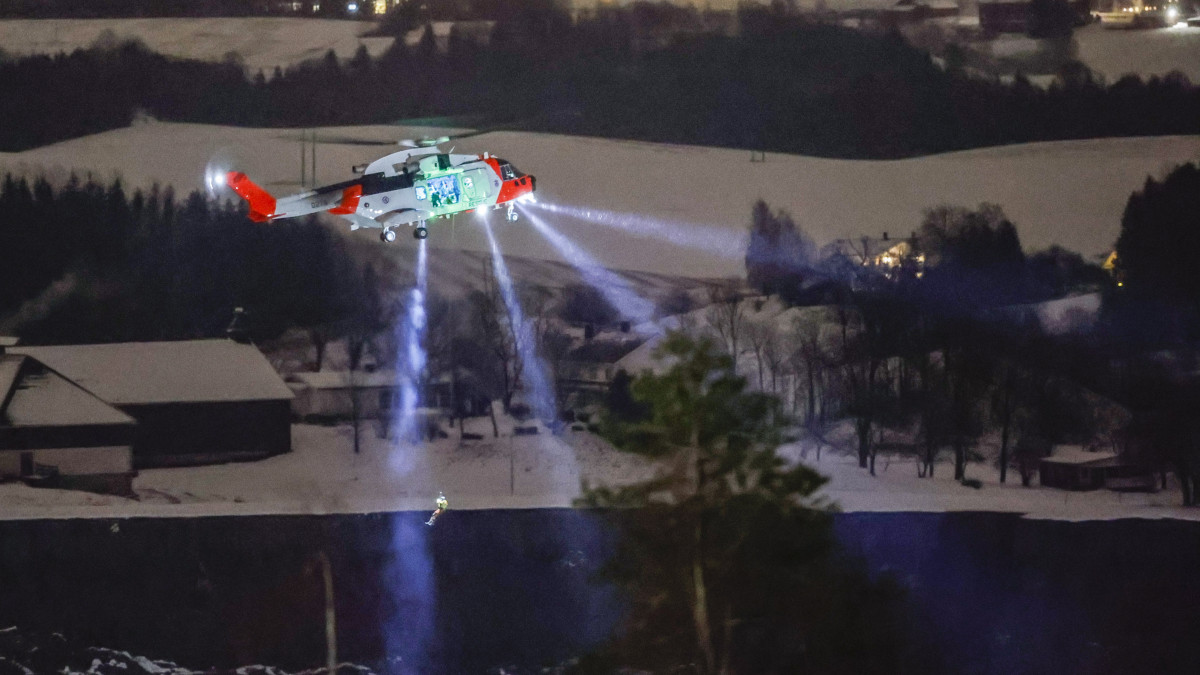Leeresztenek egy embert egy mentőhelikopterről a korábbi földcsuszamlás helyszíne felett az Oslótól mintegy 40 kilométerre, északra fekvő Ask településen 2020. december 30-án. A norvég rendőrség közleménye szerint még több embert keresnek.