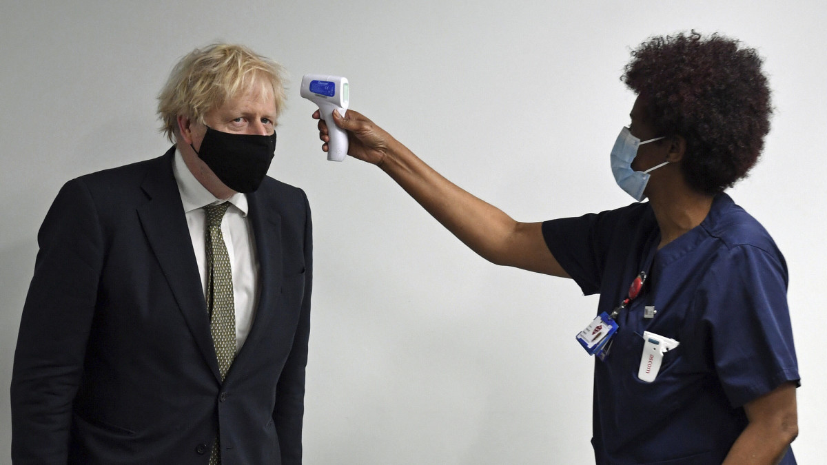 Boris Johnson brit miniszterelnök testhőmérsékletét mérik, amikor látogatást tesz az észak-londoni Chase Farm kórházban 2021. január 4-én. Nagy-Britanniában a mai napon megkezdődött az Oxfordi Egyetem és az AstraZeneca gyógyszergyár által a koronavírus ellen közösen kidolgozott oltóanyag országos alkalmazása.
