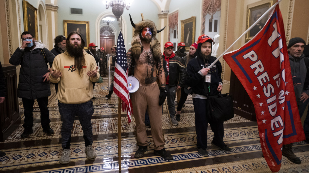 Donald Trump republikánus párti amerikai elnök tüntető támogatóinak egy csoportja a szenátusi ülésterem ajtaja előtt, miután betörtek az amerikai törvényhozás washingtoni épületébe, a Capitoliumba 2021. január 6-án. A támadás miatt félbeszakították a kongresszus két házának ülését, amelyen várhatóan hivatalosan is véglegesítik a demokrata párti jelölt, Joe Biden győzelmét hozó november 3-i amerikai elnökválasztás eredményét.