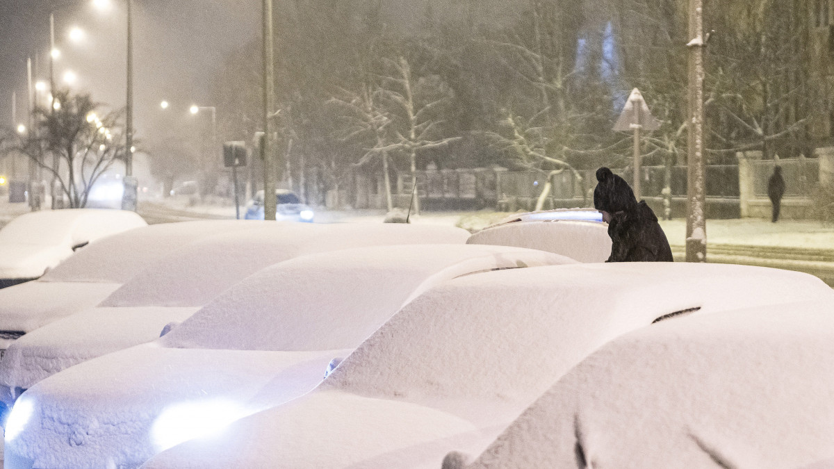 Letakarítja a havat autójáról egy férfi a nyíregyházi Sóstói úton 2021. január 13-án.