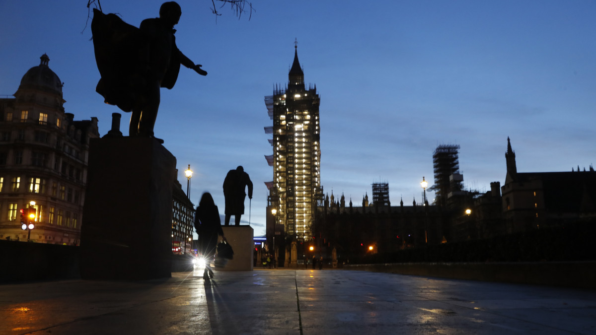 A brit parlament londoni épülete, a Westminster-palota és Winston Churchill egykori brit miniszterelnök szobra (k) a Parlament téren 2021. január 18-án hajnalban.