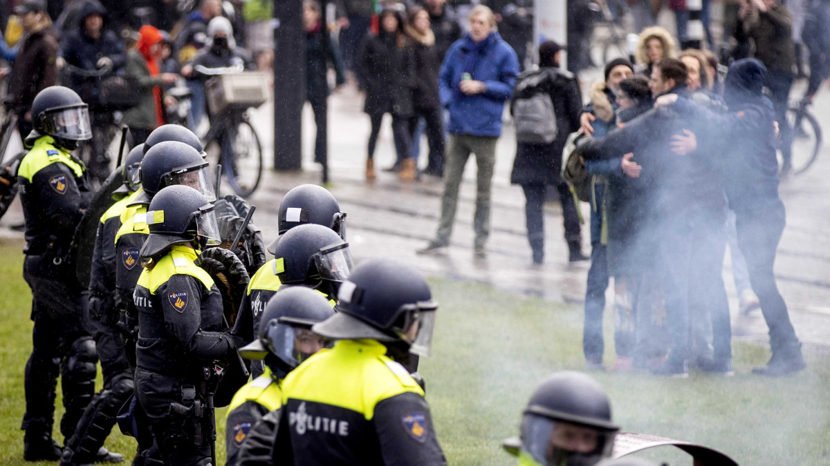 A koronavírus-járvány megfékezése érdekében bevezetett korlátozások ellen tüntető emberek összecsapnak a rohamrendőrökkel Amszterdamban 2021. január 17-én.