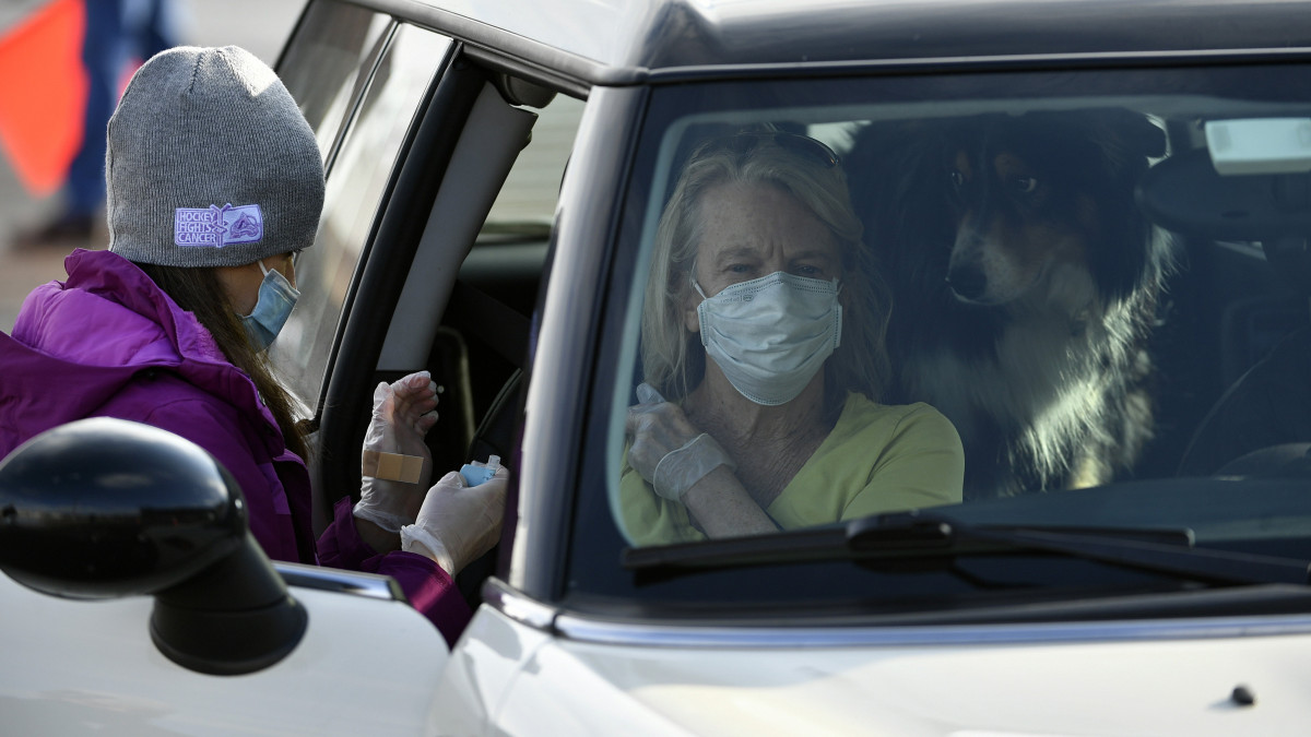 Koronavírus-elleni védőoltás kap egy autóban ülő asszony a Coors Field baseballstadion parkolójában létesített oltóközpontban a Colorado állambeli Denverben 2021. január 24-én.