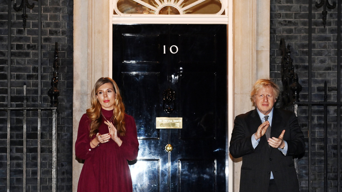 Boris Johnson brit miniszterelnök és partnere, Carrie Symonds tapsol a Sir Tom Moore II. világháborús brit veteran emléke előtti tisztelgésen a londoni kormányfői rezidencia, a Downing Street 10 előtt 2021. február 3-án. Moore-t január 31-én koronavírus fertőzés miatt kórházba szállították, ahol február 2-án, 100 éves korában elhunyt. Moore kapitány 2020 tavaszán vált híressé, amikor járókeretére támaszkodva megtett száz kört a kertjében, és ennek teljesítésével csaknem 33 millió fontot gyűjtött a brit Országos Egészségügyi Szolgálat (NHS) koronavírus-járvány elleni harcának támogatására. Ennek elismeréseként II. Erzsébet királynő a Sir előnév viselésére jogosító lovagi rangra emelte a veteránt.