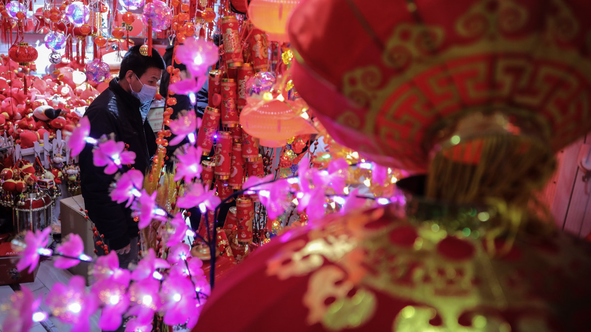 A holdújév megünneplésére készülő emberek újévi dekorációk között válogatnak egy pekingi piacon 2021. február 1-jén. A kínai holdnaptár szerint idén február 12-én köszönt be az új év, amely az állatövek szerint jelölt tizenkét esztendő közül a bivaly éve lesz.
