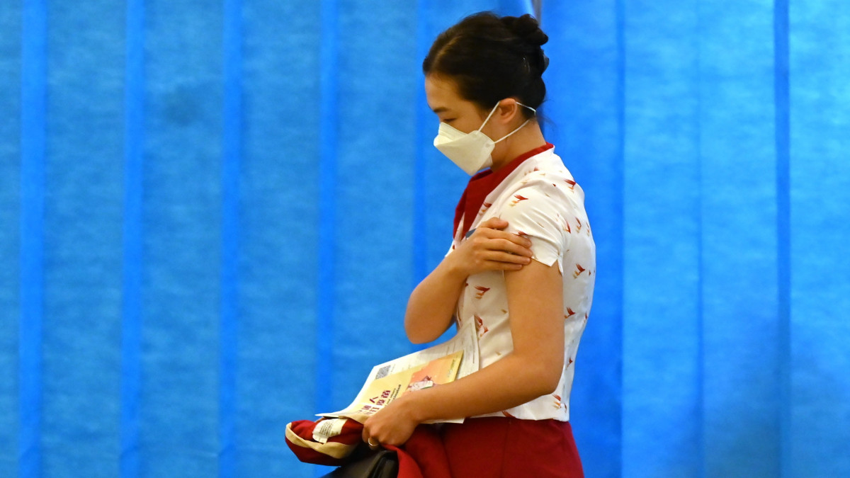 Koronavírus elleni vakcinával beoltott légiutas-kísérő távozik az oltópontról Hongkongban 2021. február 23-án.