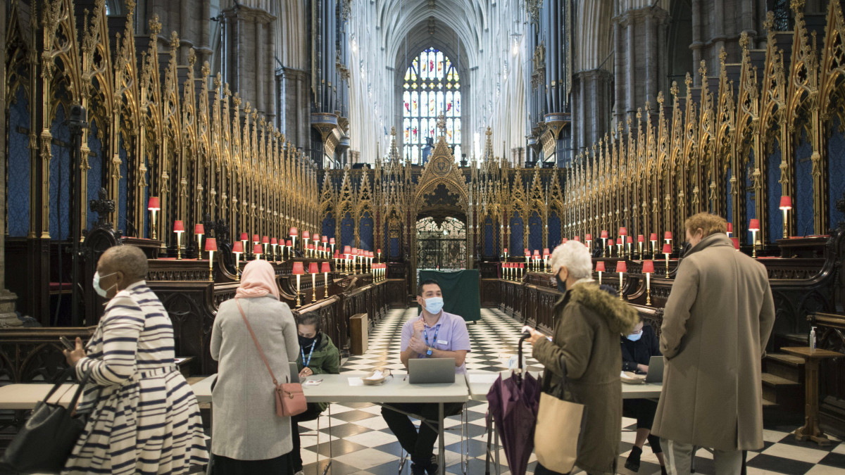 Emberek érkeznek a koronavírus elleni oltás felvételére a londoni Westminster-apátságban kialakított oltóközpontban 2021. március 10-én.