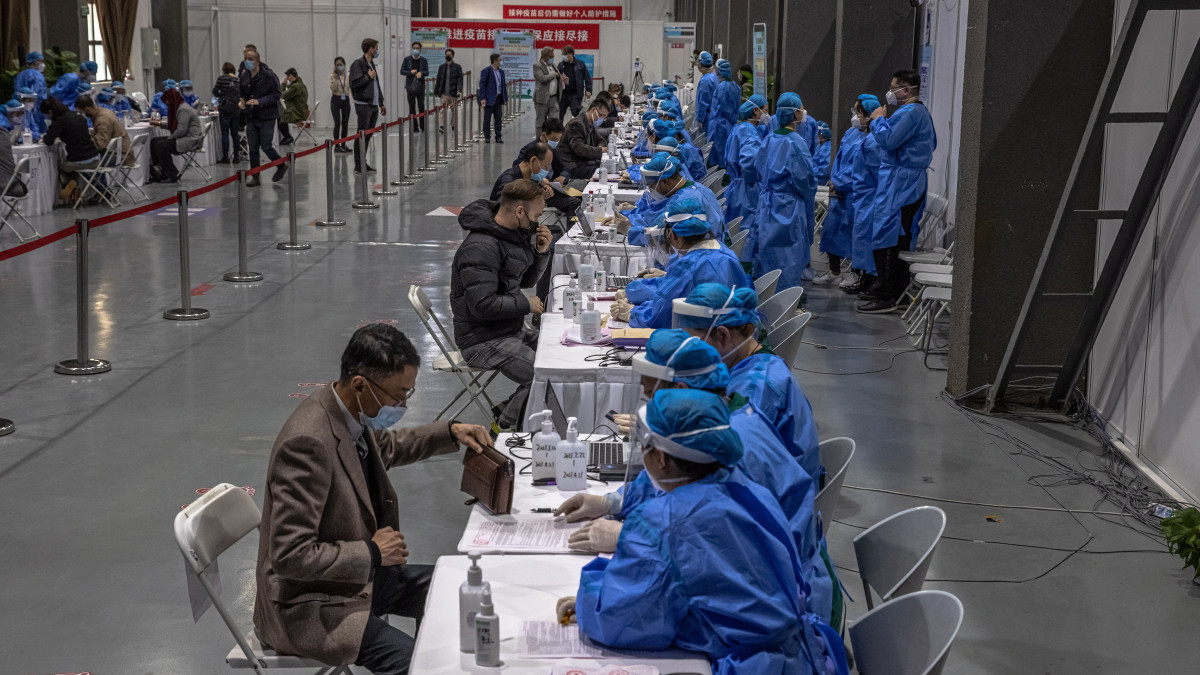 Egészségügyi dolgozók külföldi tudósítókat regisztrálnak koronavírus elleni vakcinára egy pekingi oltóközpontban 2021. március 23-án.