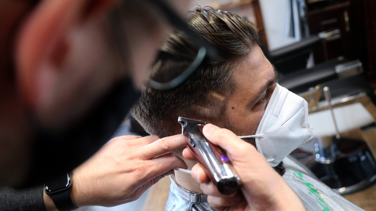 Juhos Gergő fodrász egy férfi haját vágja egy újranyitott miskolci szalonban 2021. április 7-én. Ezen a napon lépett életbe a védelmi intézkedések lépcsőzetes feloldásának első fokozatáról szóló jogszabály, amely szerint a szolgáltatásokkal kapcsolatos ideiglenes védelmi intézkedések megszűnnek, így kinyithatnak a fodrászatok, kozmetikák és más szolgáltatók. Április 6-án beadták a 2,5 milliomodik koronavírus elleni védőoltást, amely a védelmi intézkedések lépcsőzetes feloldása első fokozatának feltétele volt.