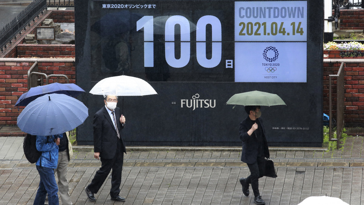 A tokiói nyári olimpiáig még hátralévő időt számláló óra előtt mennek védőmaszkos gyalogosok a japán fővárosban 2021. április 14-én, száz nappal az olimpiai játékok kezdete előtt. A koronavírus egész világra kiterjedő járványa miatt elhalasztott tokiói olimpiát 2021. július 23. és augusztus 8. között rendezik.