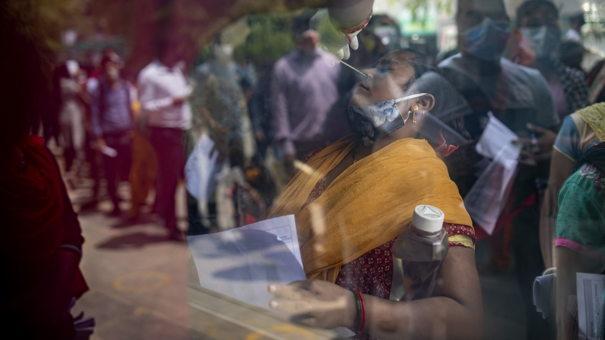 Vizsgálati mintát vesznek koronavírus-tesztre egy nőtől az Újdelhi szomszédságában fekvő Noidában 2021. április 15-én. Indiában rekordszámú, 200 ezer új koronavírus-fertőzöttet regisztráltak az elmúlt 24 órában, ezzel április eleje óta több mint a duplájára nőtt az igazolt fertőzések napi növekménye.