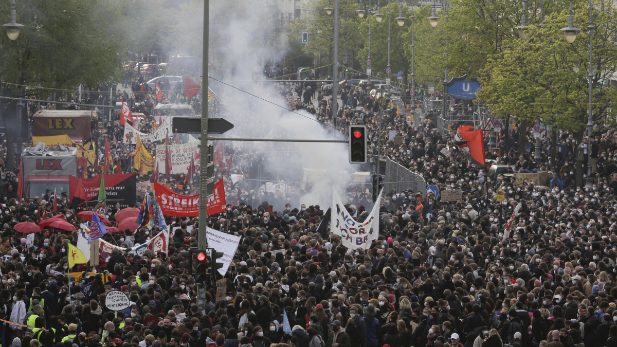 A munka ünnepének alkalmából tüntetők fölött petárda füstje gomolyog Berlinben 2021. május 1-jén.