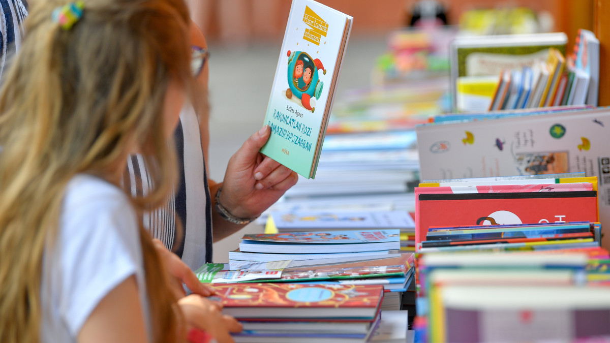 Egy érdeklődő gyermekkönyvet tart a kezében a 90. Ünnepi Könyvhét és 18. Gyermekkönyvnapok debreceni helyszínén a megnyitó napján, 2019. június 13-án.