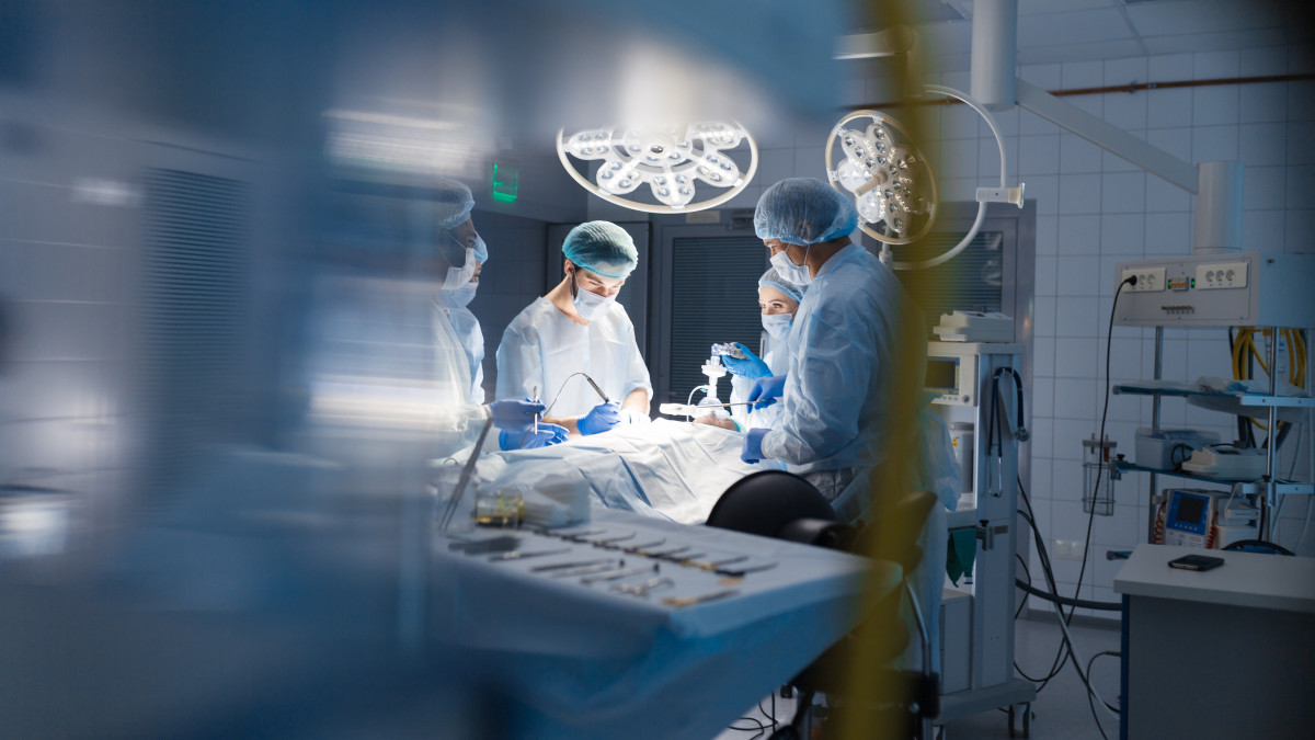 Blurred shot of group of professional surgeons at work in operating room. Emergency case, surgery, medical technology, health care cancer and disease treatment concept