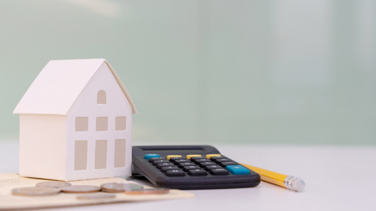 close up houses model on banking account book with calculator, coin and pencil on table for planning of home loan mortgage refinance or retention interest rates , business and financial concept