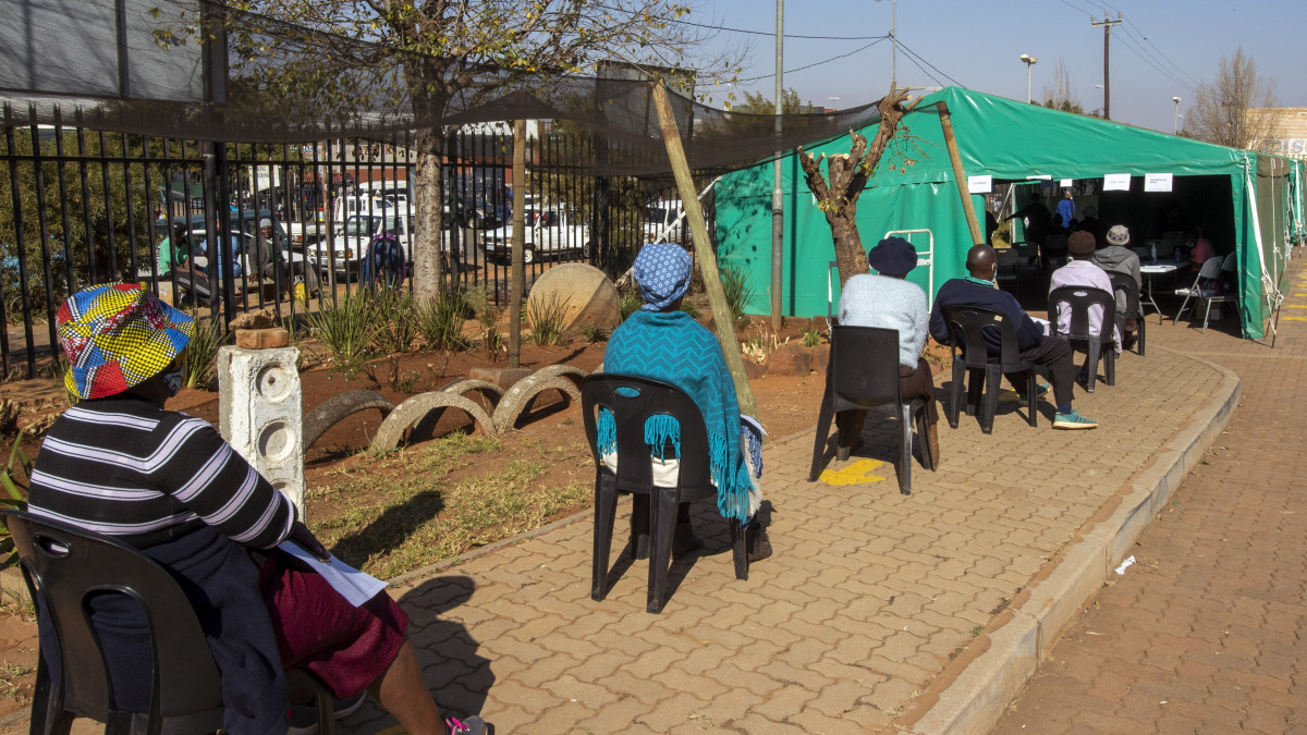 Nyugdíjasok széken ülve várják, hogy beoltsák őket a német-amerikai fejlesztésű Pfizer/BioNTech koronavírus elleni vakcinájával egy klinika udvarán felállított sátorban Johannesburg közelében 2021. május 24-én. Dél-Afrikában június végéig 5 millió idős embert szeretnének beoltani.