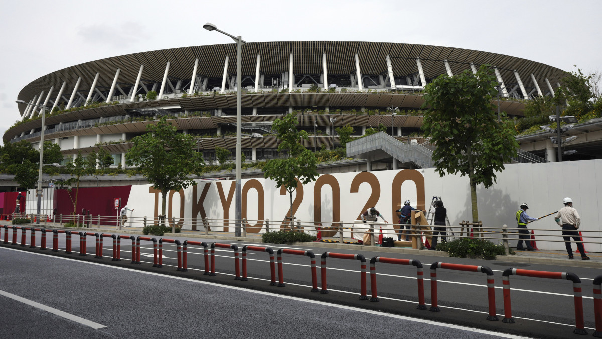 Munkások dekorálják a tokiói új Nemzeti Stadion körüli kerítést Tokióban 2021. június 1-jén. Itt rendezik a koronavírus-járvány miatt 2020-ról 2021-re halasztott ötkarikás játékok megnyitó ünnepségét.