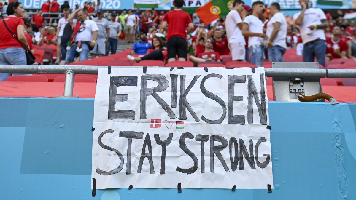 Szurkolók üzenete a dán Christian Eriksennek a koronavírus-járvány miatt 2021-re halasztott 2020-as labdarúgó Európa-bajnokság F csoportjának első fordulójában játszott Magyarország - Portugália mérkőzés előtt a Puskás Arénában 2021. június 15-én. A 29 éves Eriksen június 12-én az Eb-újonc finnek elleni összecsapás 43. percében mindenféle előzmény nélkül összeesett a pályán, ahol bő tíz percen keresztül élesztették újra, mielőtt szállítható állapotba került. A 109-szeres válogatott játékost végül stabil állapotban vitték kórházba, ahol már kommunikálni is tudott.