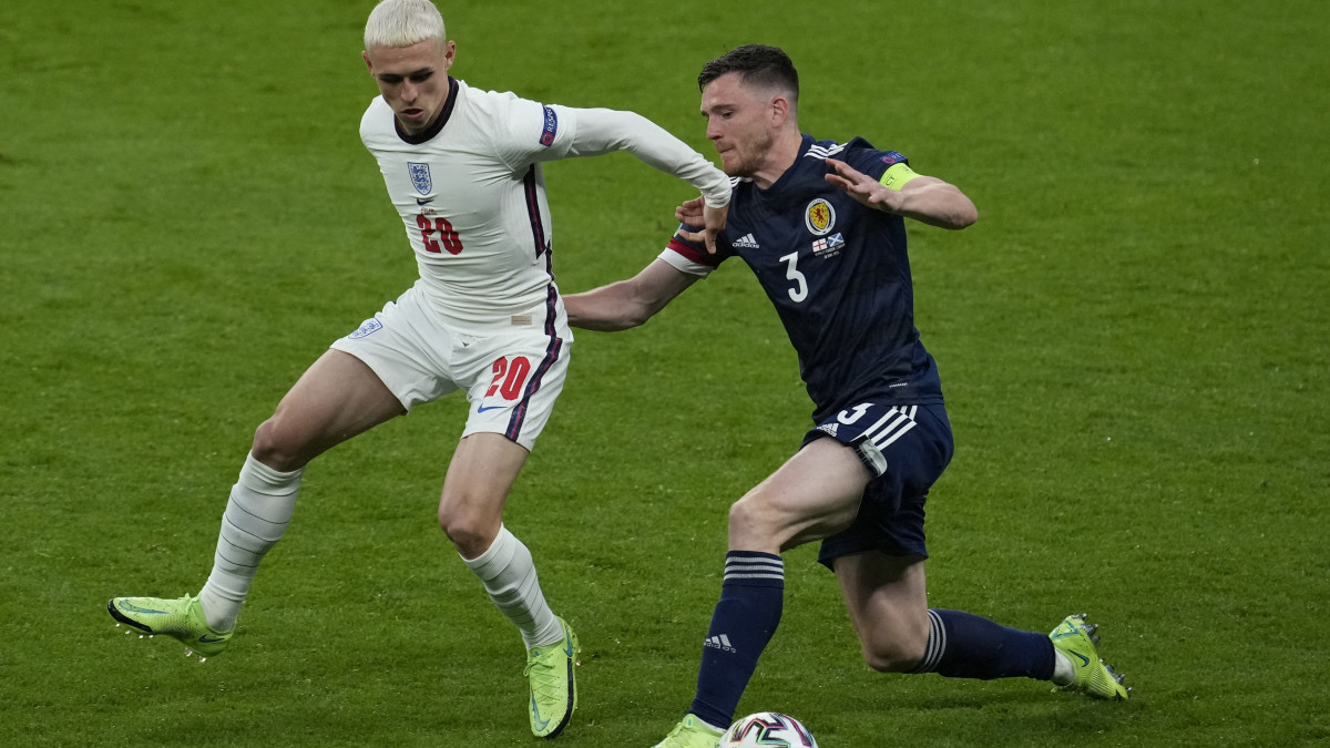 Az angol Phil Foden (b) és a skót Andrew Robertson a koronavírus-járvány miatt 2021-re halasztott 2020-as labdarúgó Európa-bajnokság D csoportjának második fordulójában játszott Anglia-Skócia mérkőzésen a  londoni Wembley Stadionban 2021. június 18-án.