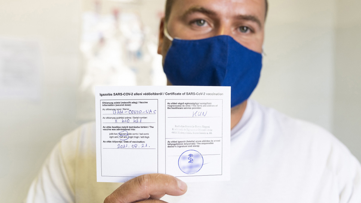 Magyar és angol nyelvű igazolását mutatja egy férfi, miután beoltották az orosz Szputnyik V koronavírus elleni vakcina második adagjával a Jósa András Oktatókórházban kialakított oltóponton 2021. június 21-én.