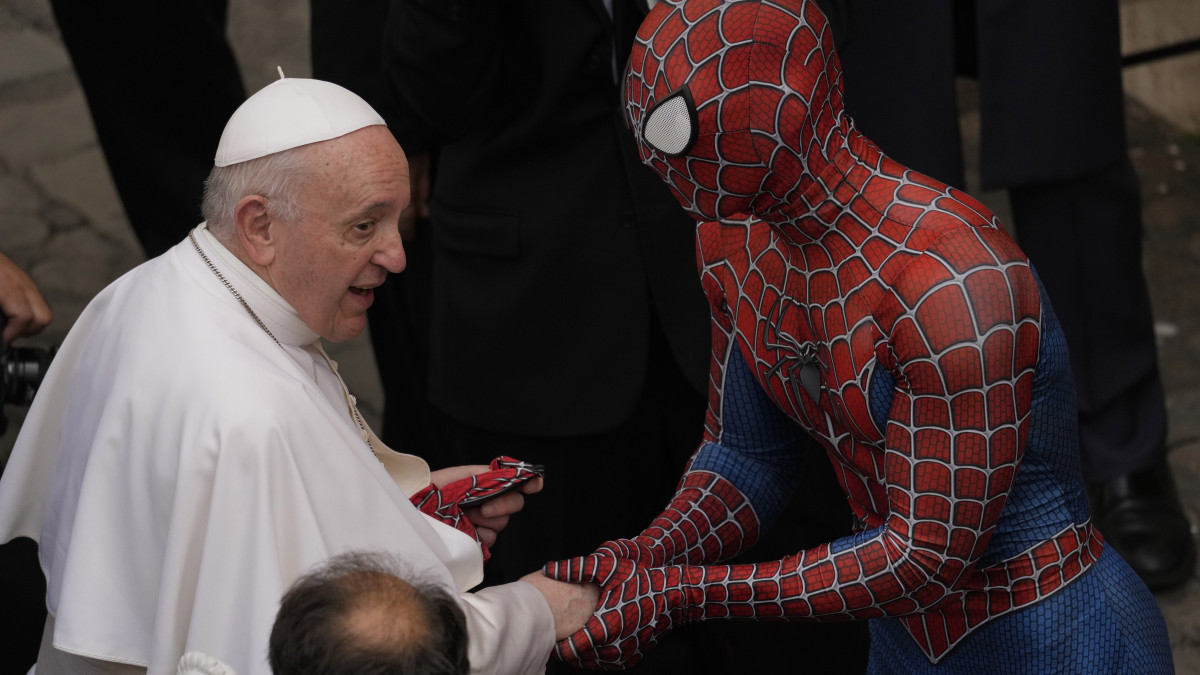 Ferenc pápa védőmaszkot kap ajándékba egy pókember-jelmezt viselő férfitől heti általános audienciája előtt a vatikáni Apostoli Palota Szent Damáz-udvarán 2021. június 23-án.