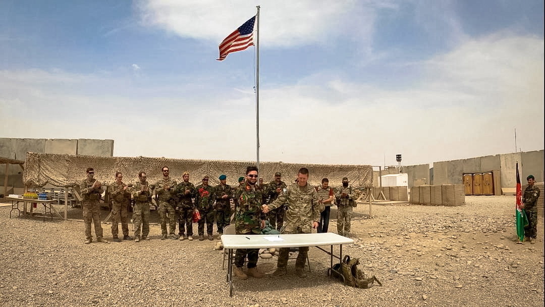 Az afgán védelmi minisztérium által 2021. május 3-án közreadott képen egy amerikai (j) és egy afgán katona kezet fog az Antonik támaszpont átadásán május 2-án. Joe Biden amerikai elnök április közepén jelentette be, hogy a NATO országaival közösen kivonulnak Afganisztánból a New York- i terrortámadás huszadik évfordulójáig, szeptember 11-ig.
