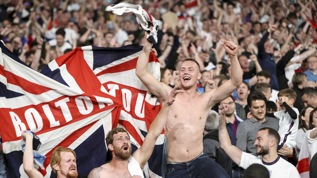Angol szurkolók ünnepelnek, miután Harry Kane csapatkapitány gólt lőtt a koronavírus-járvány miatt 2021-re halasztott 2020-as labdarúgó Európa-bajnokság elődöntőjében játszott Anglia-Dánia mérkőzés hosszabbításában a londoni Wembley stadionban 2021. július 7-én. Az angol válogatott 2-1-re győzött.