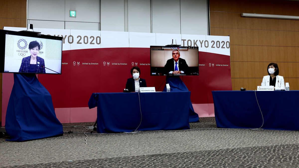 Hasimoto Szeiko, a világméretű koronavírus-járvány miatt 2021-re halasztott 2020-as tokiói nyári olimpiát és paralimpiát előkészítő bizottság elnöke (b2), Marukava Tamajo olimpiaügyi miniszter (j) valamint Juriko Koike tokiói kormányzó (b, kivetítőn) és Thomas Bach, a Nemzetközi Olimpiai Bizottság, a NOB elnöke (j2, kivetítőn) megbeszélést folytat a japán fővárosban 2021. július 8-án. A koronavírus-járvány újabb hulláma miatt rendkívüli állapotot hirdetett a japán kormány negyven napra Tokióban; ebben az időszakban, július 23. és augusztus 8. között rendezik az ötkarikás játékokat.