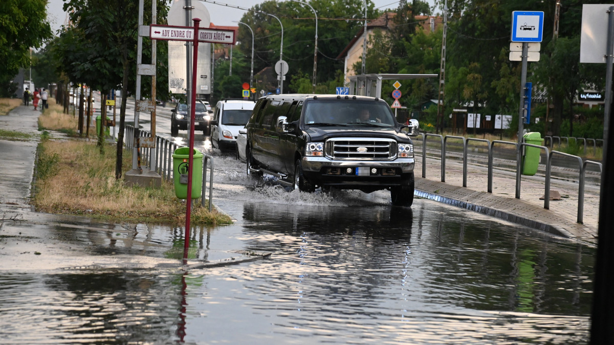 Autók haladnak a felhőszakadás után esővízzel elárasztott úton Budapesten, a XIX. kerületben 2021. július 9-én. Az esőzés miatt több kerületben is korlátozásokra kell készülniük az autósoknak és a tömegközlekedéssel utazóknak.