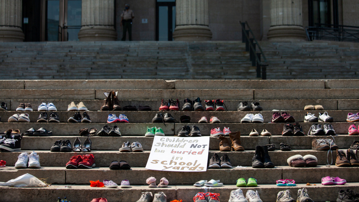 WINNIPEG, CANADA - JULY 02: Shoes placed on the steps of the Manitoba Legislature to honour hundreds of children recently discovered in unmarked graves on the sites of several former residential schools across Canada near the now toppled statue of Queen Victoria on July 2, 2021 in Winnipeg, Manitoba, Canada. The statue was pulled down by indigenous protestors following a march to honour survivors and victims of CanadaĂ˘s residential school system. The shoes were placed during an event calling for the recognition of genocide at Canadian residential schools (Photo by Daniel Crump/Anadolu Agency via Getty Images)