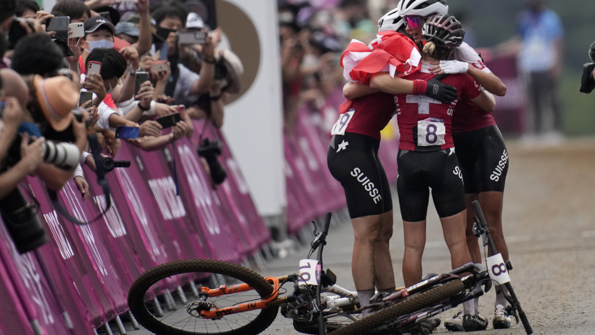 Az aranyérmes svájci Jolanda Neff és honfitársai, az ezüstérmes Sina Frei és a bronzérmes Linda Indergand ünnepel a női hegyikerékpárosok terepversenyének végén az Izui Hegyikerékpáros Pályán Izuban 2021. július 27-én.