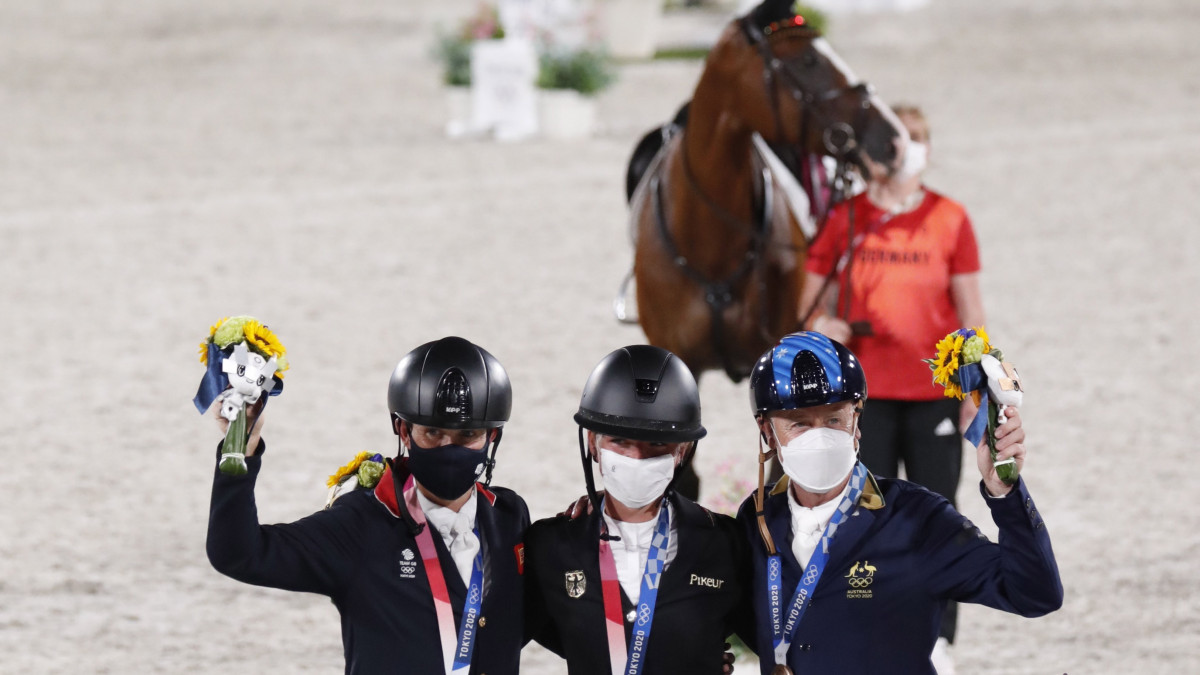 Az ezüstérmes brit Tom McEwen, az aranyérmes német Julia Krajewski és a bronzérmes ausztrál Andrew Hoy a világméretű koronavírus-járvány miatt 2021-re halasztott 2020-as tokiói nyári olimpia lovastusája csapatversenyében a Lovasparkban 2021. augusztus 2-án.