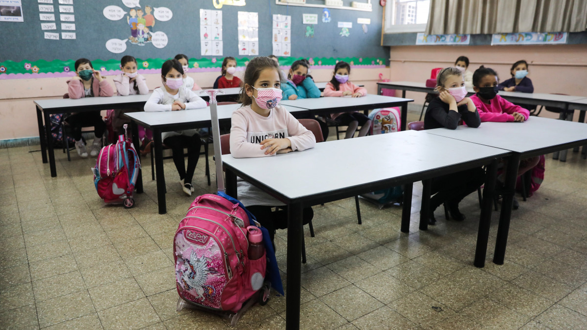 Diákok ülnek a tanteremben egy újranyitott jeruzsálemi iskolában 2021. február 21-én, a szombati munkaszüneti nap után kezdődő hét első napján. Izraelben megnyíltak a boltok, a bevásárlóközpontok, a piacok, valamint a kulturális- és sportintézmények, valamint újraindultak számos újabb településen az iskolák.
