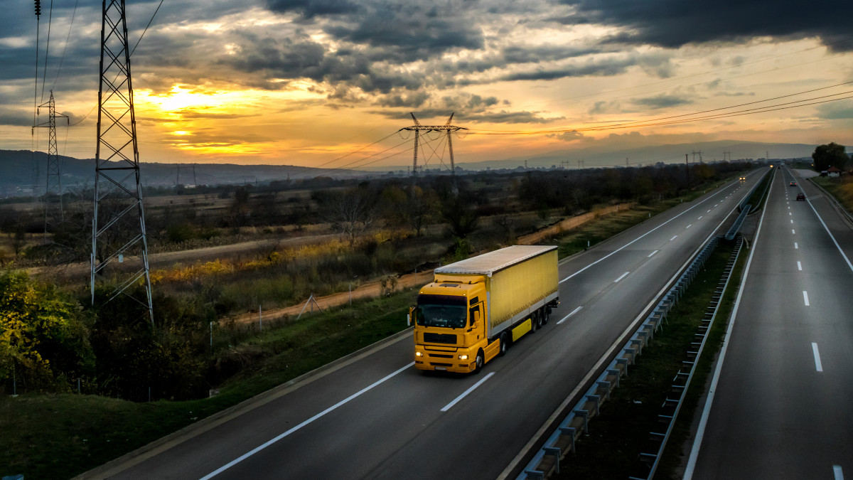 Highway transportation with yellow lorry at sunset