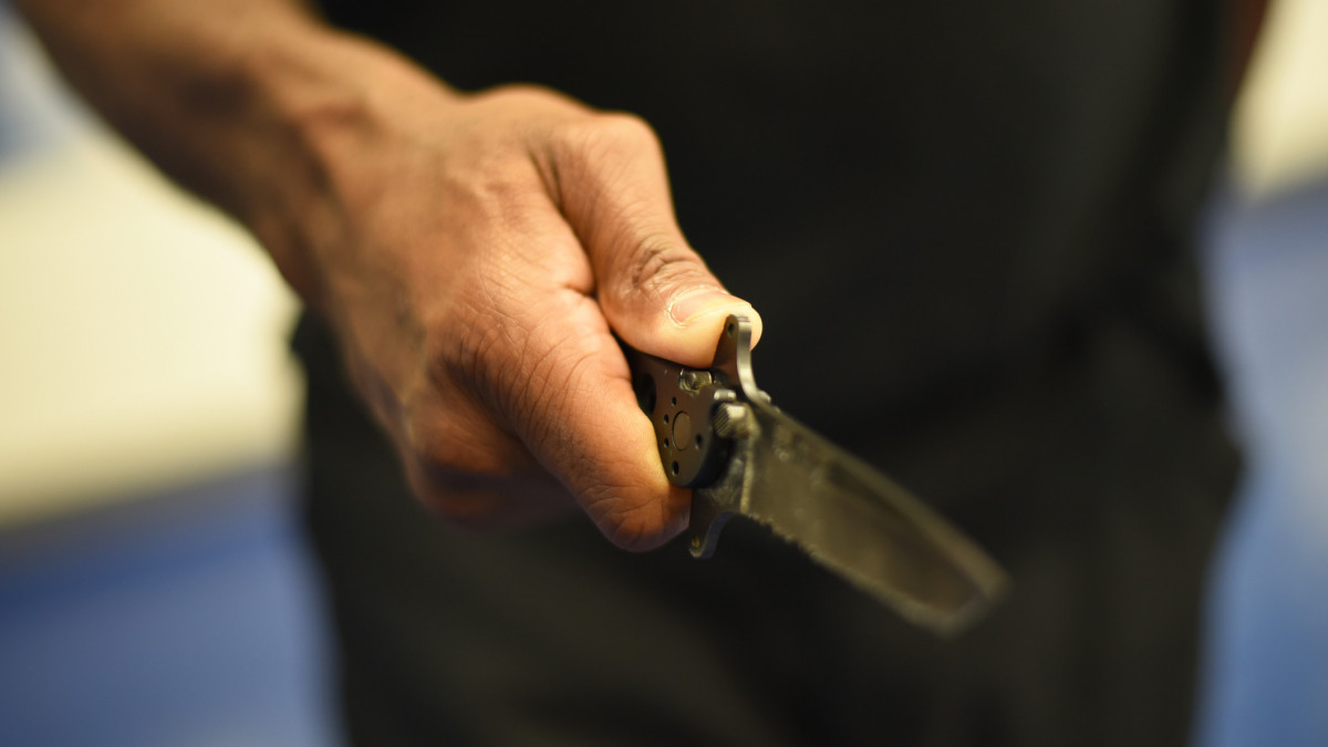 Close up on an adult black males hand holding a knife