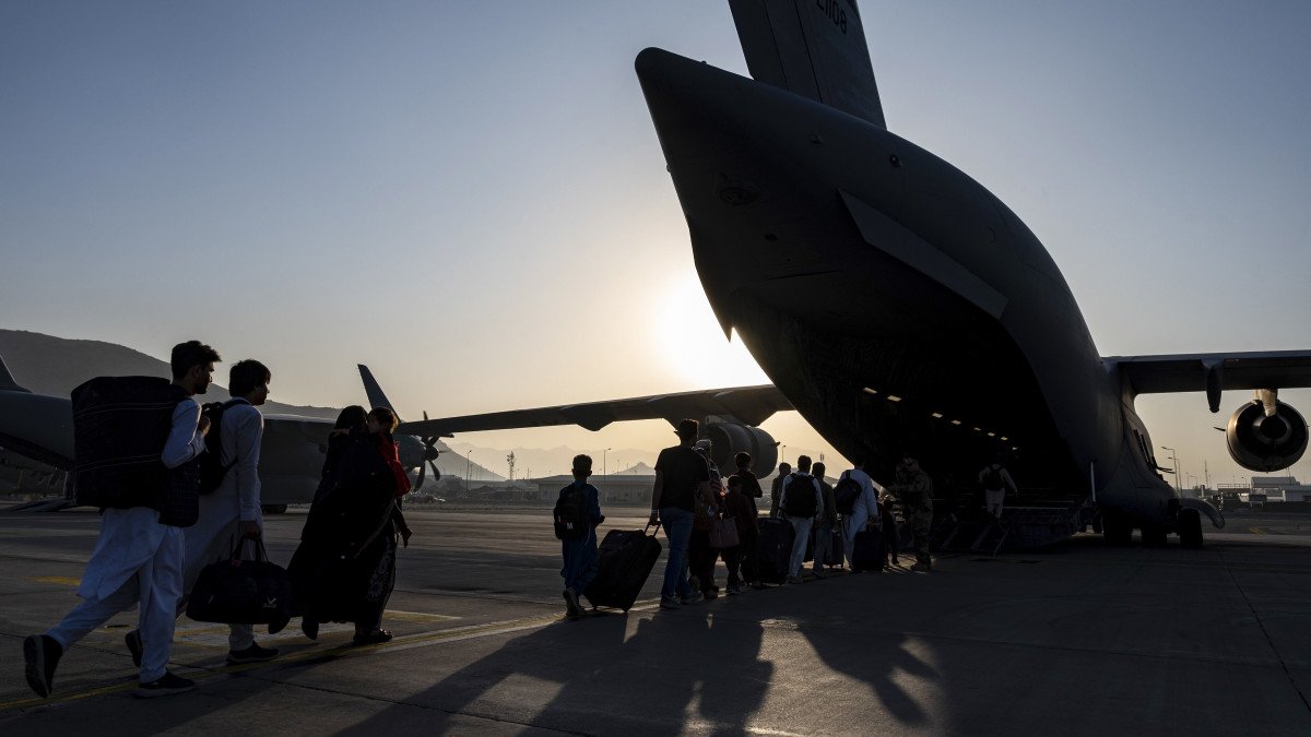 Az amerikai légierő által közreadott képen afgánok beszállnak egy C-17 Globemaster III amerikai katonai teherszállító repülőgépbe a kabuli Hamid Karzai Nemzetközi Repülőtéren 2021. augusztus 24-én. Az Egyesült Államok és szövetségesei a légi kikötőn keresztül menekítik ki a külföldi állampolgárokat és a velük együttműködő afgánokat, miután az iszlamista tálibok elfoglalták Afganisztán csaknem egészét.