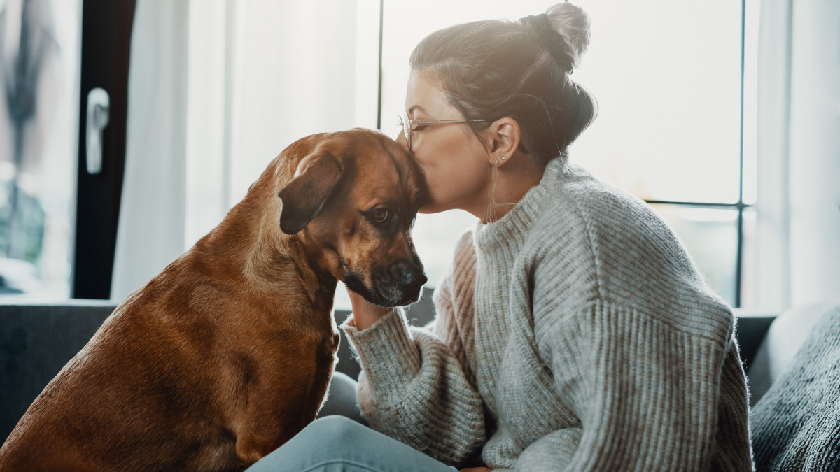 Woman cuddles, plays with her dog at home because of the corona virus pandemic covid-19