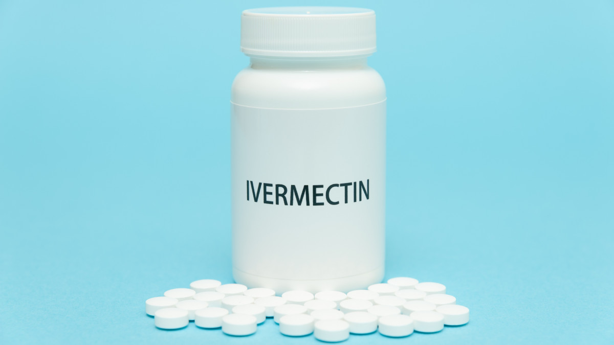 Treatments for Coronavirus (COVID-19): IVERMECTIN in white bottle packaging with scattered pills. Isolated on blue background. Horizontal shot.