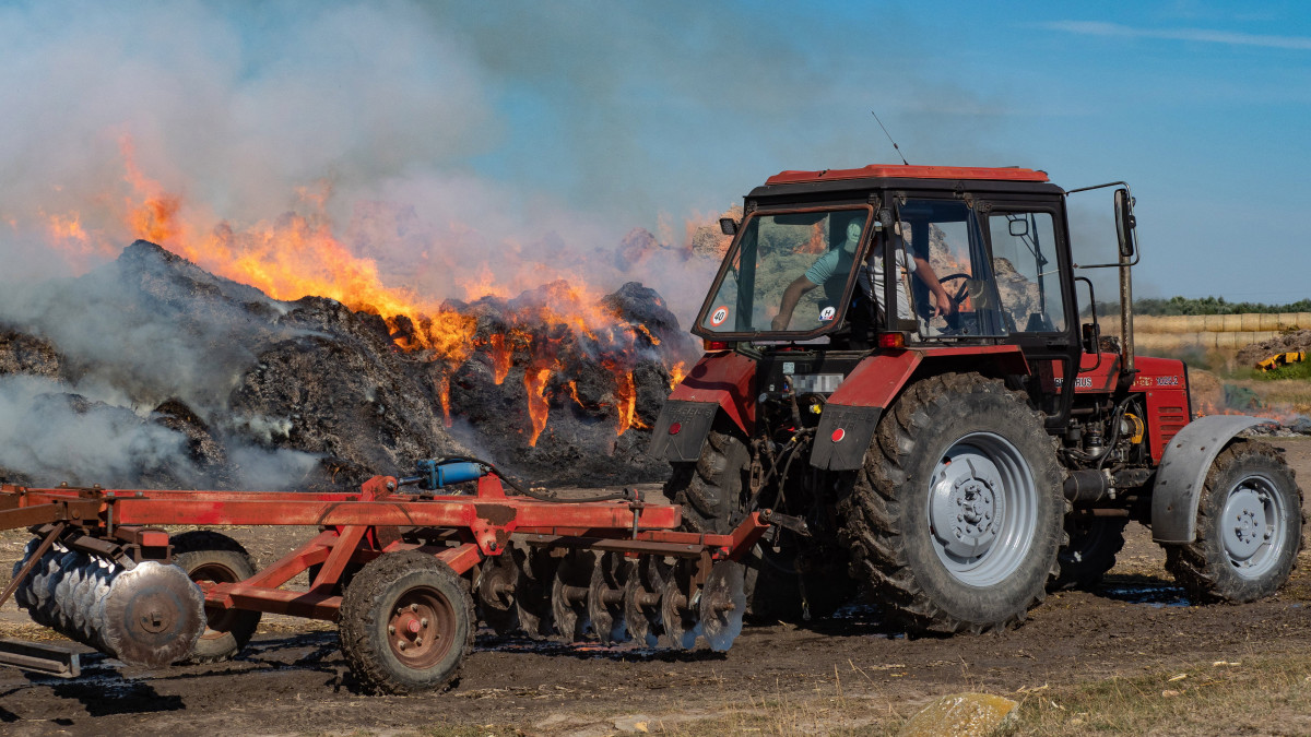 Égő körbálák oltásán dolgozik egy munkagép a Bács-Kiskun megyei Újsolt határában 2021. szeptember 9-én. Körülbelül kétezer körbála kapott lángra egy tanya területén. Mintegy 850 birka és egyéb jószágok téli takarmánya veszett oda a tűzben.