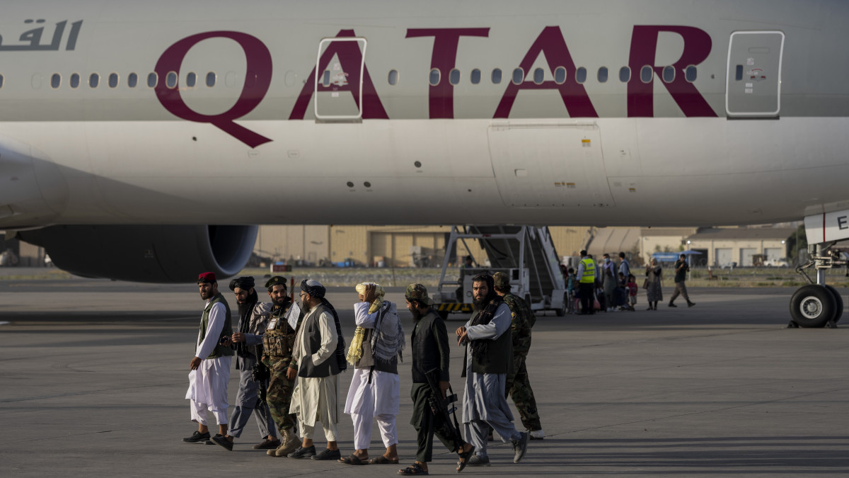 Tálib harcosok haladnak el a Qatar Airways egyik járata előtt a kabuli repülőtéren 2021. szeptember 9-én. A Kabulból Dohába tartó repülőgép az első  járat az amerikaiak által szervezett óriási légihíd óta, amelynek keretében több mint 120 ezer embert sikerült evakuálni a tálibok váratlan augusztusi hatalomátvétele után. Az utasszállító gép fedélzetén kétszáz kimenekített külföldi utazott.
