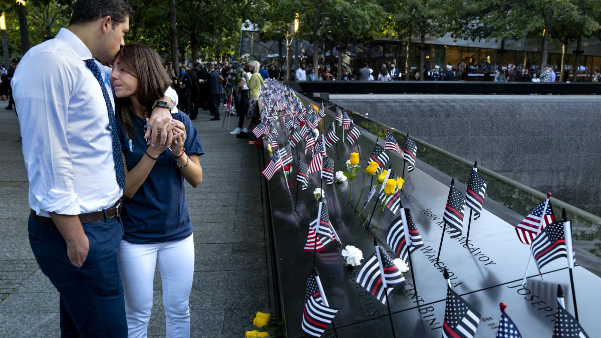 NEW YORK, NEW YORK - SEPTEMBER 11: Katie Mascali is comforted by her fiance Andre Jabban as they stand near the name of her father Joseph Mascali during a ceremony at the National September 11 Memorial & Museum commemorating the 20th anniversary of the September 11th terrorist attacks on the World Trade Center on September 11, 2021 in New York City. The nation is marking the 20th anniversary of the terror attacks of September 11, 2001, when the terrorist group al-Qaeda flew hijacked airplanes into the World Trade Center, Shanksville, PA and the Pentagon, killing nearly 3,000 people. (Photo by Craig Ruttle - Pool/Getty Images)
