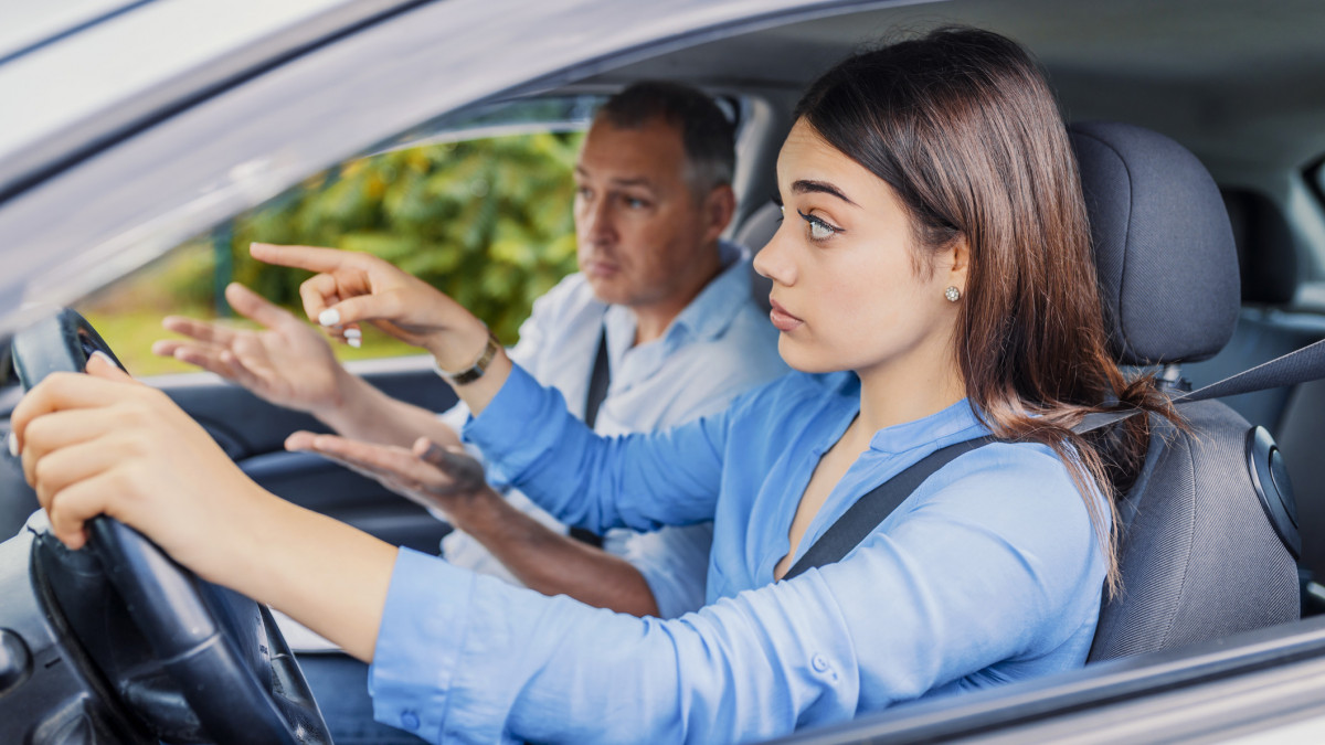 Smiling woman Learns to Drive in Car with instructor. Learning to Drive . Student driver taking driving test. Woman taking driving lessons from instructor