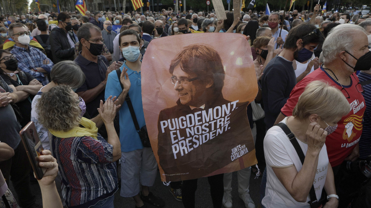 Carles Puigdemont függetlenségpárti EP-képviselőt és volt katalán elnököt ábrázoló képet tart egy tüntető a volt elnök őrizetbe vétele elleni tüntetésen a barcelonai olasz konzulátus épülete előtt 2021. szeptember 24-én. A kép alatti felirat jelentése Puigdemont az elnökünk. Puigdemontot előző nap őrizetbe vették Olaszországban, egy 2019. október 14-én kelt európai elfogatóparancs alapján történt.