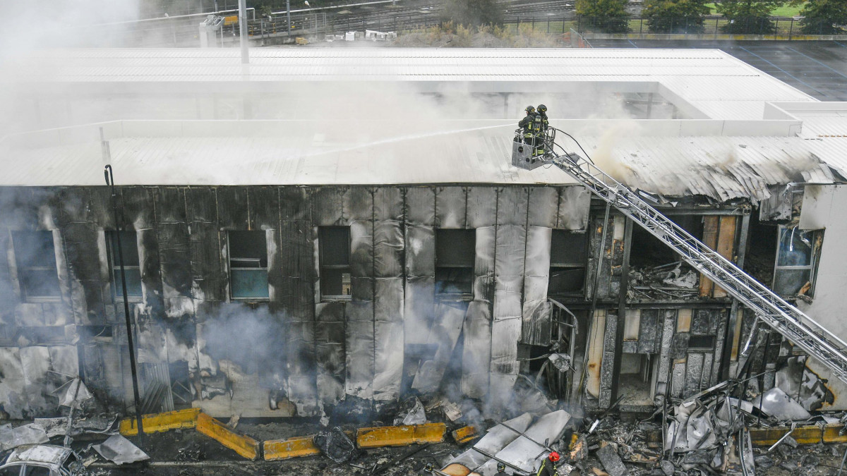 Tűzoltók dolgoznak a repülőgép-szerencsétlenség helyszínén Milánó külvárosában 2021. október 3-án, miután egy öt utast és egy pilótát szállító kisrepülőgép egy irodaházra zuhant. A balesetet senki sem élte túl.