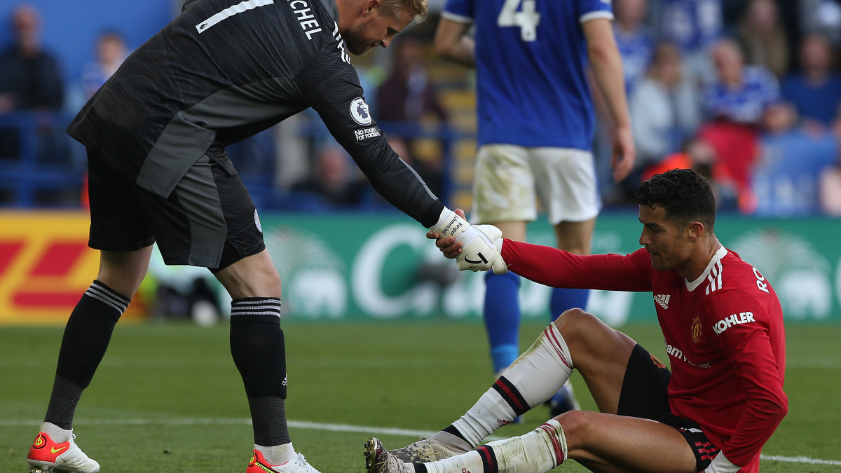 LEICESTER, ENGLAND - OCTOBER 16: Cristiano Ronaldo of Manchester United is helped up by Kasper Schmeichel of Leicester City during the Premier League match between Leicester City and Manchester United at The King Power Stadium on October 16, 2021 in Leicester, England. (Photo by Matthew Peters/Manchester United via Getty Images)